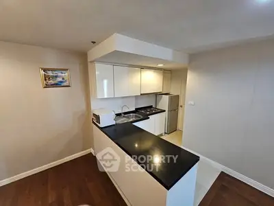 Modern kitchen with sleek black countertops and white cabinets in a cozy apartment.
