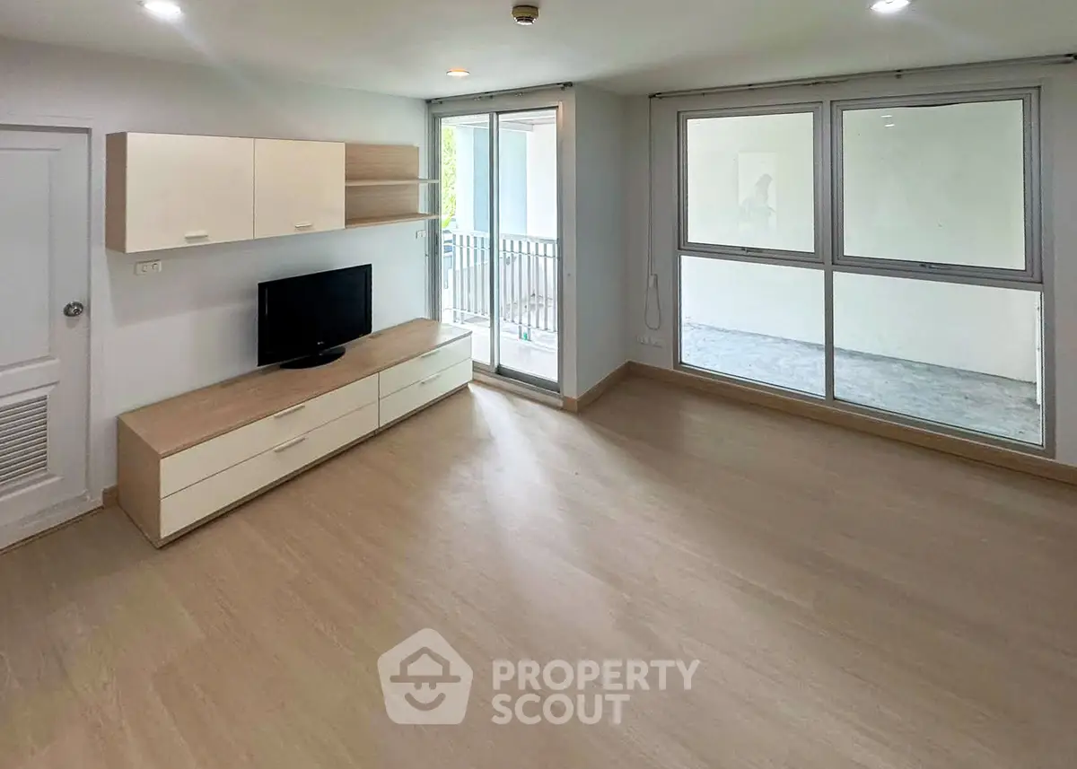 Spacious living room with modern design and large windows leading to a balcony.