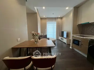 Modern living room with dining area and kitchen, featuring sleek furniture and contemporary design.