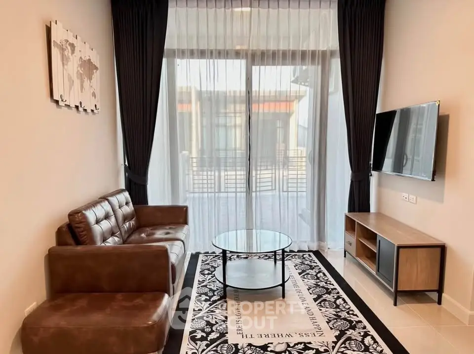 Modern living room with leather sofa, glass coffee table, and wall-mounted TV, featuring elegant curtains and stylish decor.