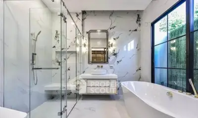 Luxurious modern bathroom with marble walls, glass shower, and freestanding bathtub.