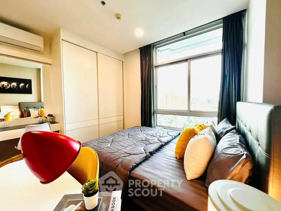 Modern bedroom with large window and stylish decor in a cozy apartment.
