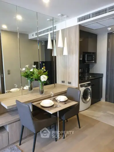 Modern kitchen with dining area, featuring sleek appliances and stylish decor in a compact layout.