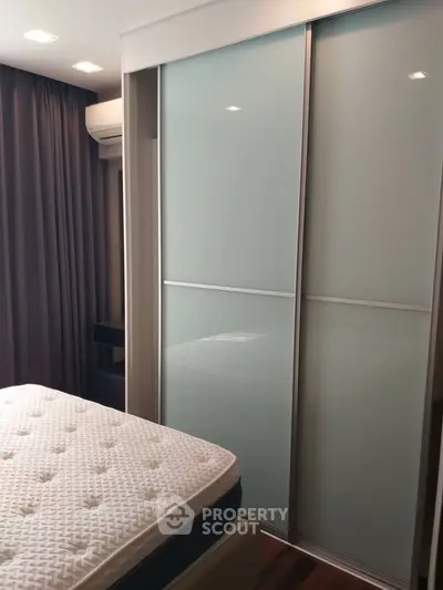 Modern bedroom with sleek sliding closet doors and comfortable mattress.