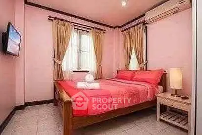Cozy bedroom with pink decor and natural light, perfect for relaxation.
