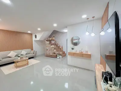 Modern living room with stylish decor and open staircase, featuring elegant lighting and cozy seating area.