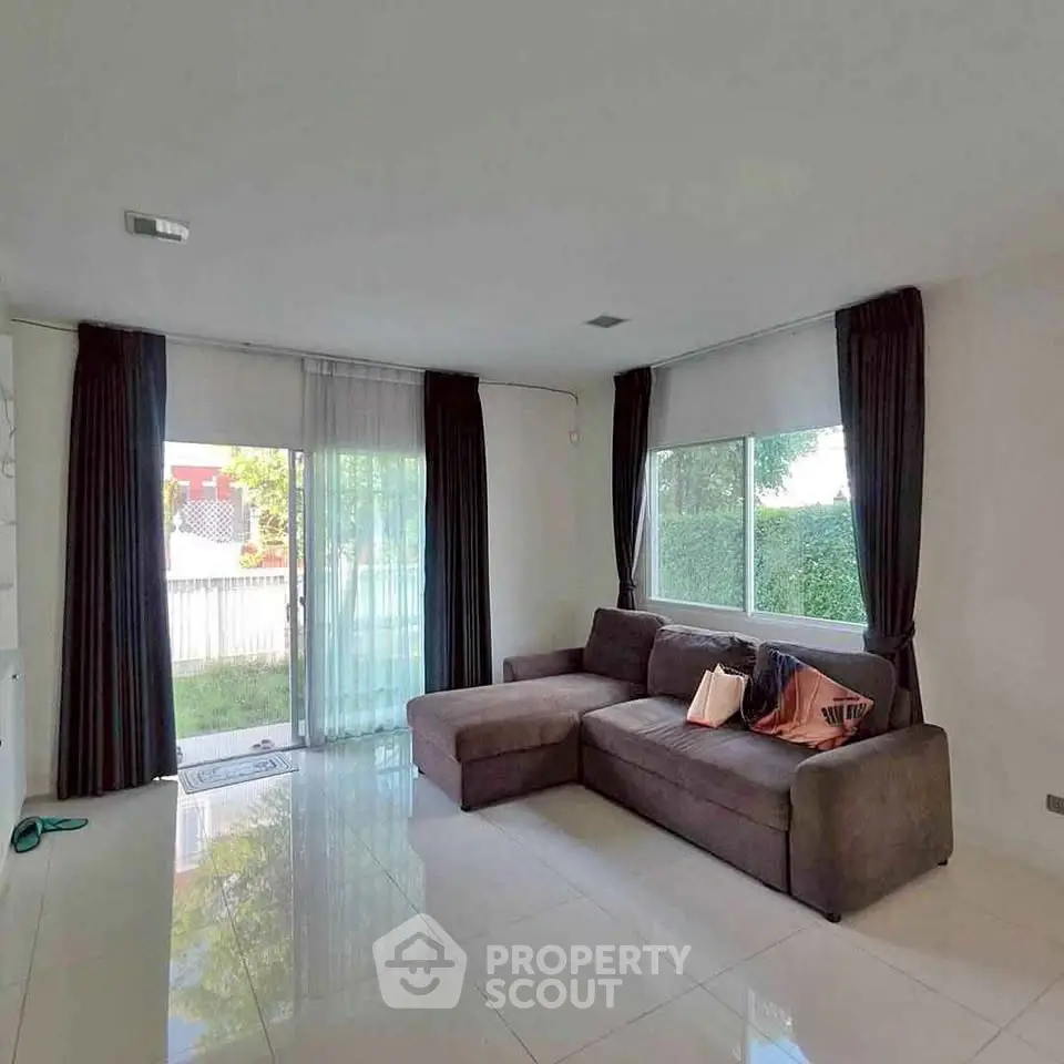 Spacious living room with large windows and modern sectional sofa, offering a bright and inviting atmosphere.