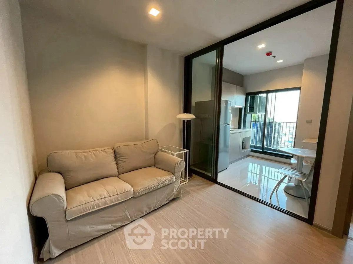 Modern apartment with cozy living room and sleek kitchen, featuring a comfortable sofa and dining area with balcony view.
