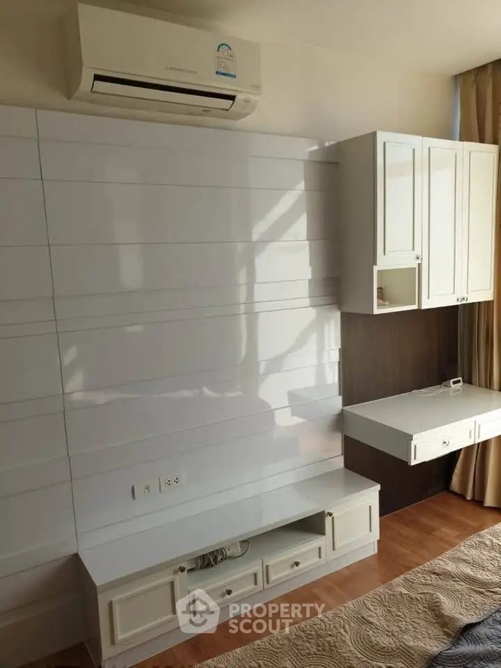 Modern living room with built-in storage and air conditioning, featuring elegant wood flooring and natural light.