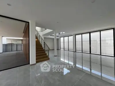 Spacious modern living room with large windows and elegant staircase