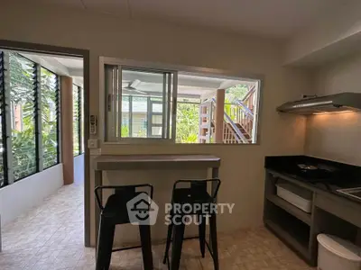 Charming kitchen with open layout and bar seating, offering a view of the outdoor staircase and greenery.