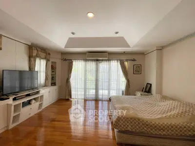 Spacious bedroom with large windows and wooden flooring in a modern home.