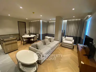 Luxurious modern living room with elegant furniture and dining area, featuring stylish lighting and wooden flooring.