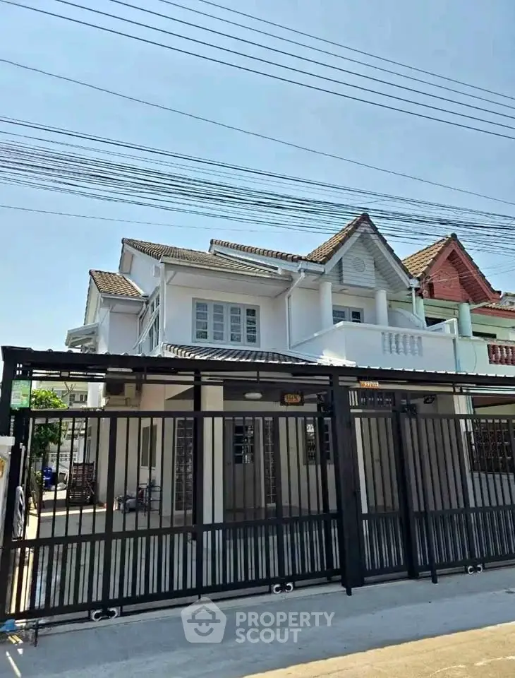 Charming two-story house with gated entrance and classic architectural design.