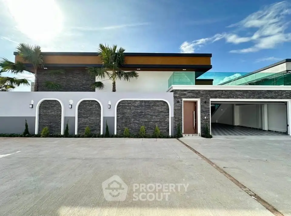 Modern luxury home exterior with sleek design and spacious garage under clear blue sky.