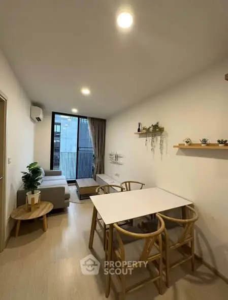 Modern living room with dining area and balcony view, featuring minimalist decor and natural light.