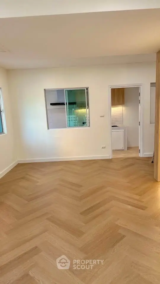 Spacious modern living room with elegant wooden flooring and open kitchen view.