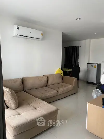 Modern living room with beige sectional sofa and air conditioning unit, perfect for relaxation.