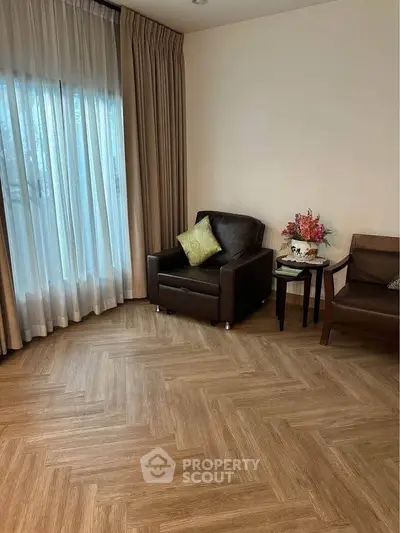 Cozy living room with elegant parquet flooring and stylish armchairs near a large window.