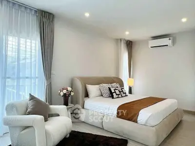 Elegant bedroom with plush bed, cozy armchair, and soft lighting in a modern home.