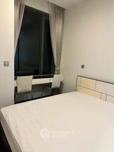 Modern bedroom with minimalist decor and large window for natural light.