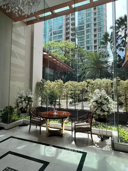 Luxurious building entrance with elegant seating and lush garden view.