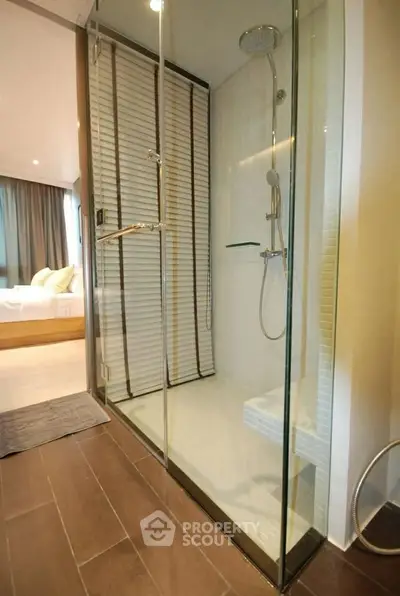 Modern bathroom with glass shower enclosure and wooden flooring