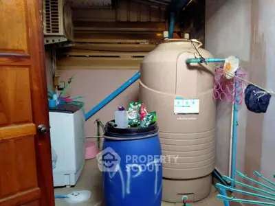 Utility room with water tank and washing machine, ideal for efficient home management.