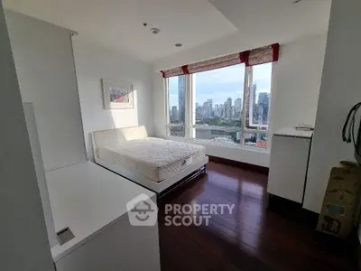 Spacious bedroom with city view and hardwood floors in modern apartment