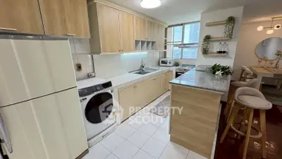 Modern kitchen with sleek cabinetry, washing machine, and breakfast bar in a stylish apartment.