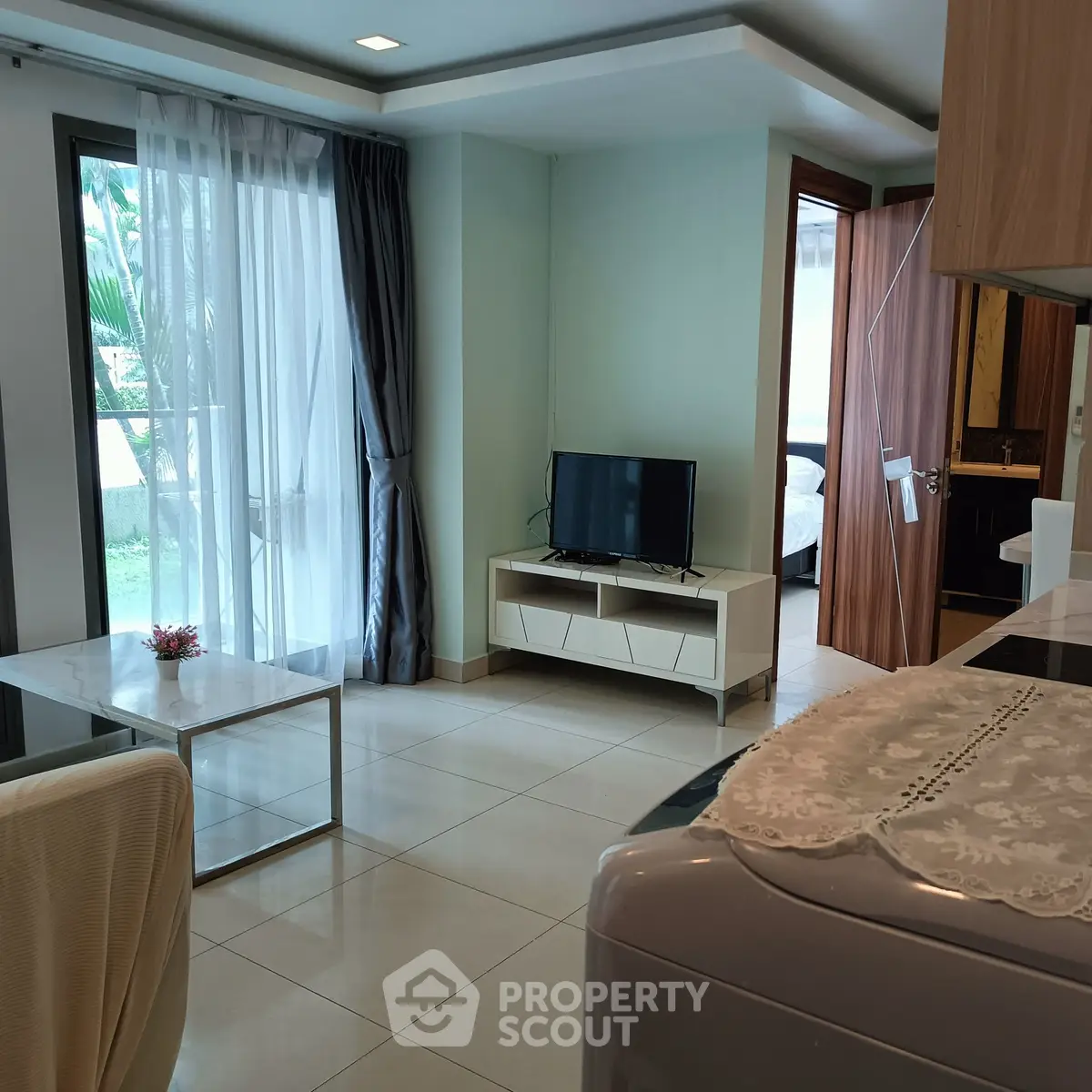 Modern living room with TV, large window, and sleek furniture in a stylish apartment.