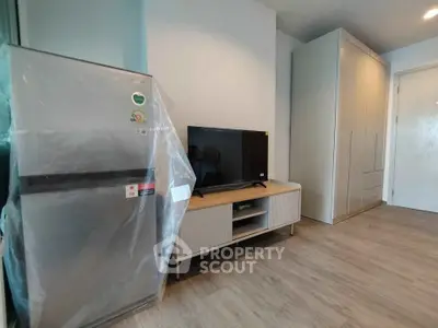 Modern apartment interior with fridge, TV, and wardrobe in a stylish living space.