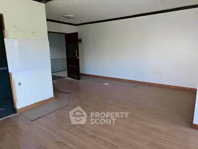 Spacious empty room with wooden flooring and white walls, ideal for customization.