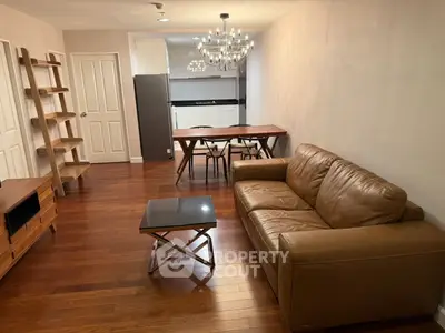 Stylish living room with leather sofa and modern chandelier in open layout apartment.