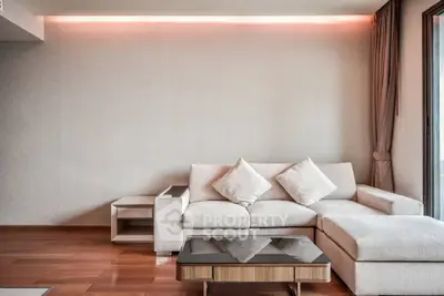 Modern living room with elegant sofa and stylish coffee table, featuring ambient lighting and wooden flooring.