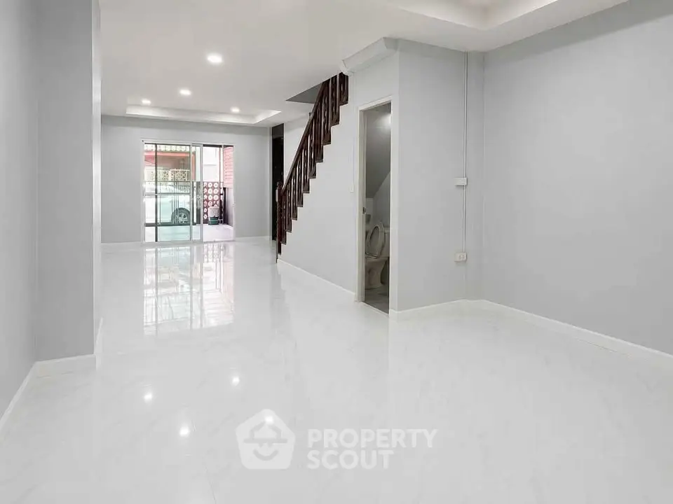 Spacious modern living room with glossy white floors and staircase