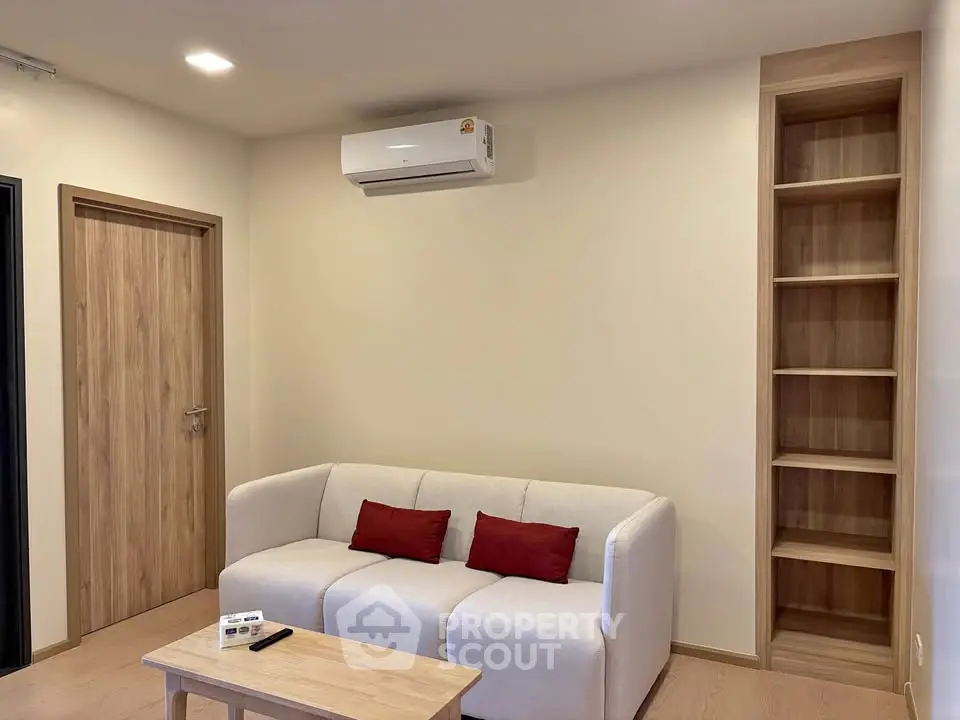 Modern living room with cozy sofa, built-in shelves, and air conditioning unit.