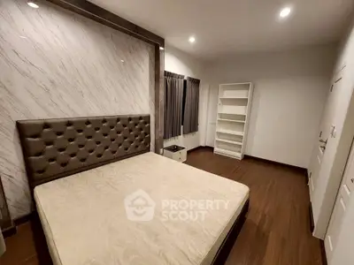 Spacious bedroom with elegant headboard and wooden flooring