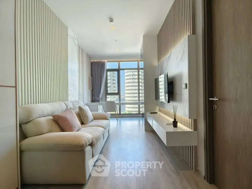 Modern living room with stylish decor and large windows offering city views.