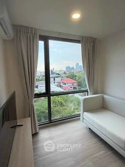 Cozy living room with large window offering stunning city view, modern sofa, and sleek TV stand.
