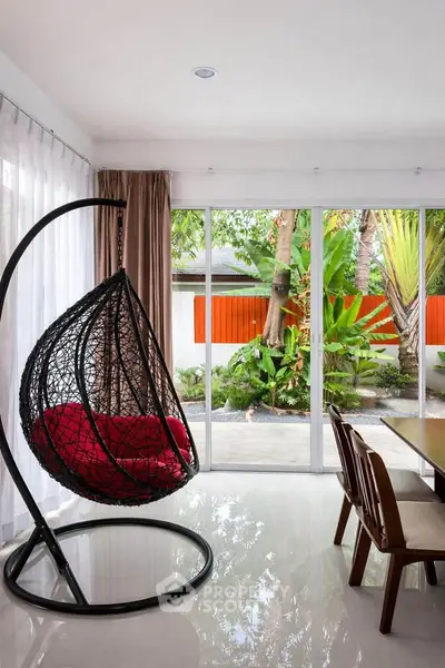 Modern living room with hanging chair and garden view through large windows.
