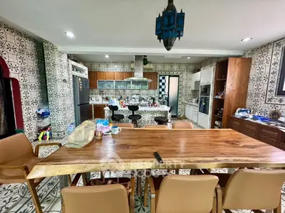 Spacious kitchen with modern appliances and stylish decor, featuring a large wooden dining table and patterned tiles.