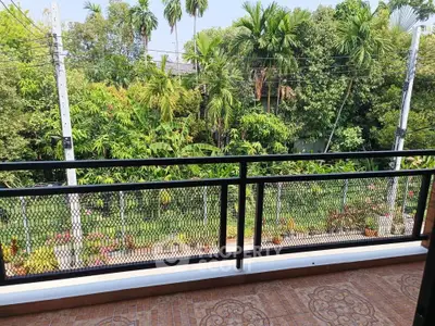 Spacious balcony with lush garden view, perfect for relaxation and enjoying nature.