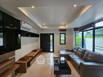 Modern living room with sleek furniture and large windows offering natural light.