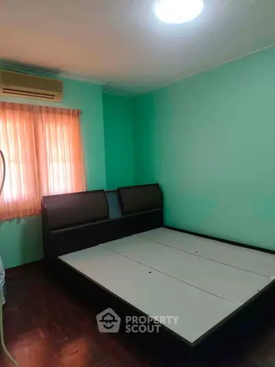 Spacious bedroom with modern bed frame and natural light from window.