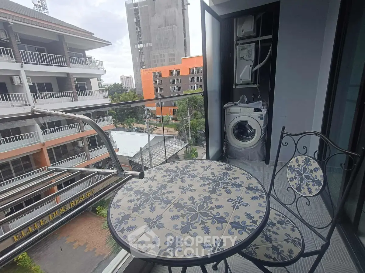 Charming balcony with washing machine and elegant seating, offering a city view.