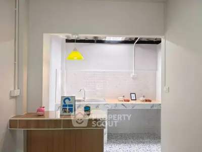 Charming kitchen with modern open layout and stylish decor, featuring a bright yellow pendant light and sleek countertops.
