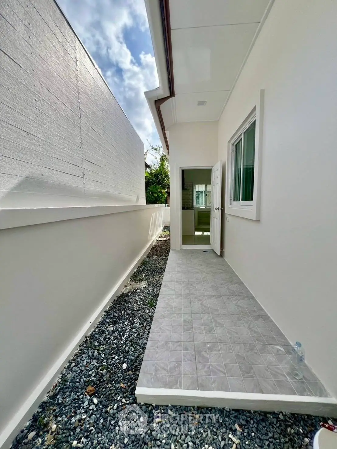 Modern side entrance with tiled pathway and gravel landscaping