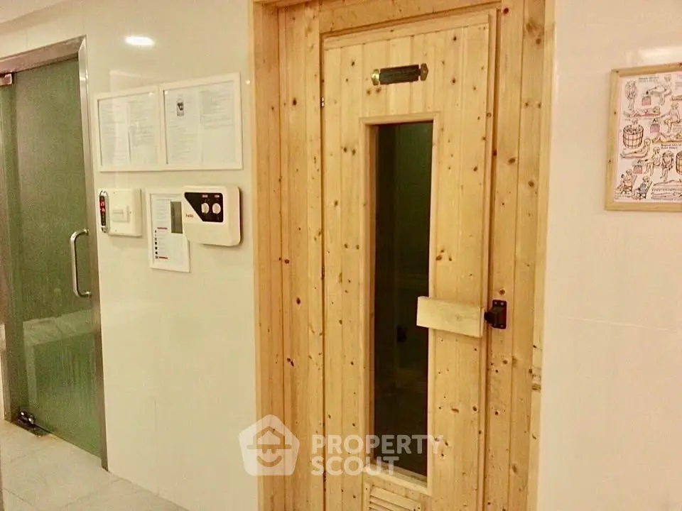 Luxurious sauna room in modern building with sleek glass door and wooden finish.