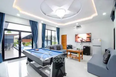 Luxurious living room with pool table and modern decor, opening to a spacious balcony with scenic views.